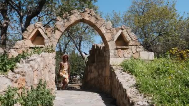 Schattig charmant meisje in gele jurk met bandjes wandelen tussen verwoeste historische deel van de stad op zomer vakantie — Stockvideo