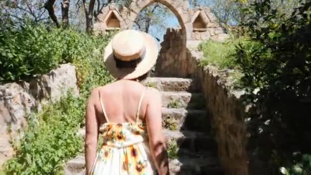 Mujer atractiva en sombrero de verano y gafas de sol caminando entre los lugares de interés histórico de la ciudad vieja. Vista trasera cercana — Vídeo de stock