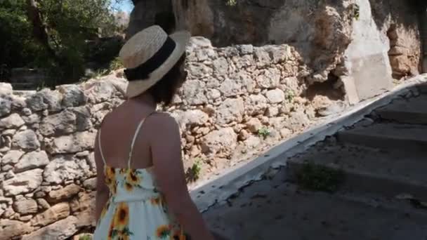 Linda mujer joven en vestido de verano y sombrero de paja con gafas de sol escalando escalones con hermosa arquitectura y sonriendo — Vídeo de stock