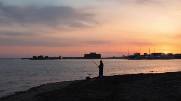 Neuvěřitelný růžový západ slunce v přístavišti s osamělým, izolovaným rybář s rybářskou tyčí na přední straně — Stock video