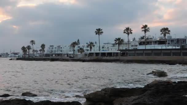 저녁 황혼에 야자수, 카페, 레스토랑이있는 빈 관광 부두. 해안과 놀라운 일몰. 회색 구름을 뚫고 고군분투하는 태양 — 비디오