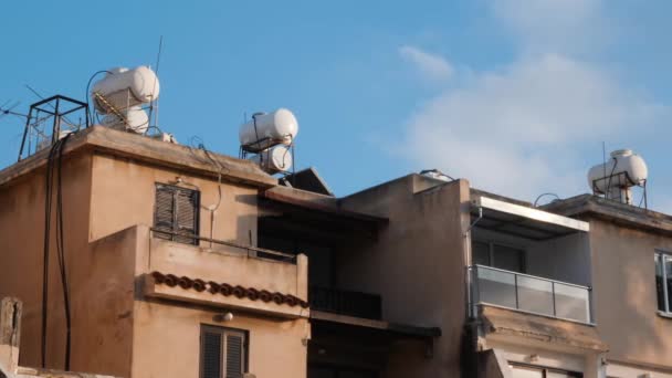 Side view of concrete house with terraces and windows and with water tanks on the roof of the building. Solar water heater boiler on rooftop — Stock Video