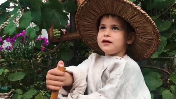 Vista lateral de cerca de niño lindo divertido feliz en sombrero de paja tratando de aprender a tocar en la flauta de madera, vista de cerca — Vídeos de Stock