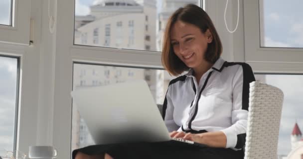 Jeune femme d'affaires attrayante souriante travaillant sur un ordinateur portable et heureuse de son travail réussi, finissant son travail, applaudissant et levant les mains — Video