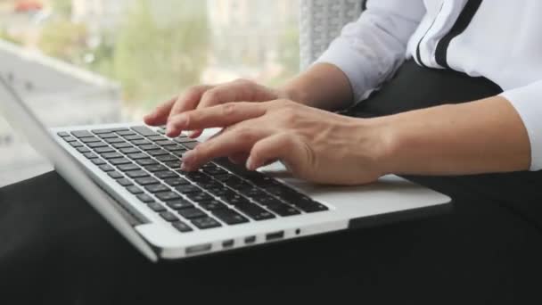 Kvinnliga händer skriva på laptop tangentbord medan i moderna kontor. Affärskvinna på laptop, närbild — Stockvideo