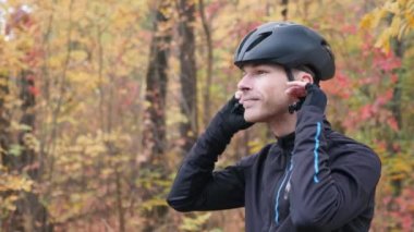 Sonbahar kenti parkında eğitime hazırlanan motive olmuş genç bir bisikletçi. Bisiklet giysili profesyonel sporcunun yan görüş portresi siyah kask ve gözlük takıyor.