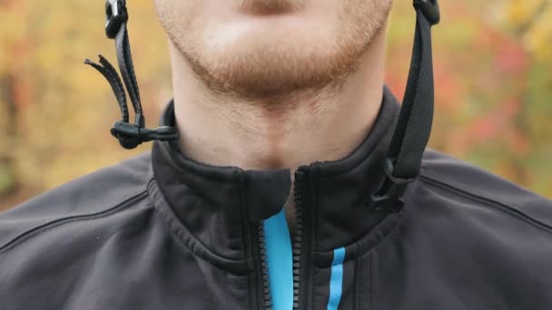 Profesional ciclista masculino cierre de cremallera en la chaqueta y el cierre del casco antes de entrenar al aire libre en bicicleta en el bosque de otoño. Vista frontal extra cercana del joven atleta que se prepara para el entrenamiento — Vídeos de Stock