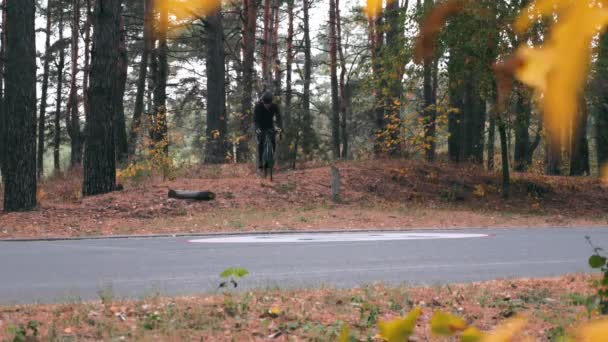 Kasklı ve spor gözlüklü genç adam yol kenarında bisiklet sürerken yoğun pedal çeviriyor. Bisiklet yarışmasından önce profesyonel bisikletçi eğitimi — Stok video