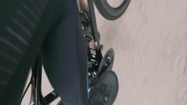Extra zblízka pohled na mužskou sportovní nohu je jízda na silničním kole. Profesionální cyklista v černé cyklistice oblečení šlapání na silničním kole, extra zblízka boční pohled — Stock video