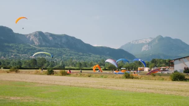 Paraplane lekce na paraglidingové stanici v Alpách. Sportovci vzlétají na padáku proti modré obloze a horám — Stock video