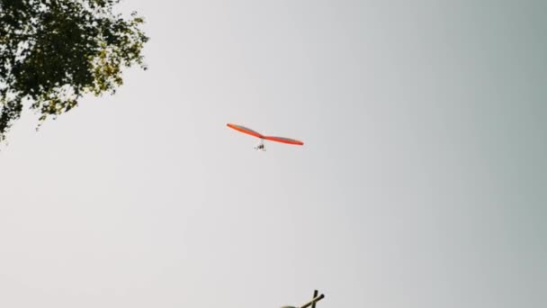 Oranje geïsoleerde deltavlieger vliegt tegen grijze bewolkte lucht. Vlieglessen deltavliegen in Alpen — Stockvideo