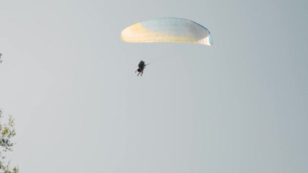 Kleurrijke geïsoleerde paraglider landt op tegen grijze bewolkte lucht boven de Alpen. Man die op paraglider vliegt — Stockvideo