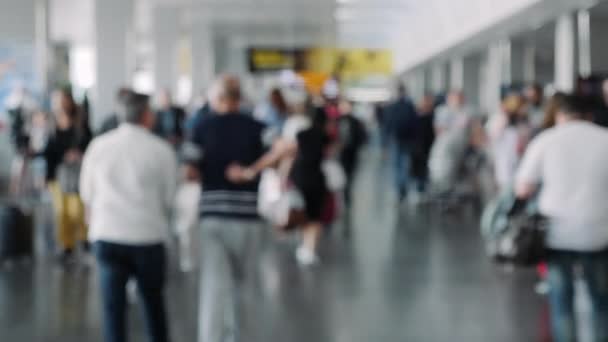 공항에 있는 사람들 이 흐릿하게 보 입니다. 여행자들은 여행 가방을 들고 공항을 걸어 다닌다. 공항에서 비행기를 기다리고 있는 남녀 관광객들. — 비디오