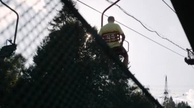 Dağlardaki bir ormandan geçen kayak koltuğu. Yazın dağda çelik kablolar olan bir sandalye.