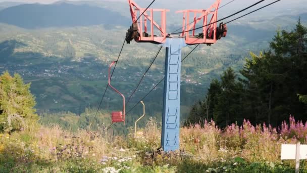 Üres hegyi sífelvonó acélkábelekkel a hegy tetején, zöld hegyekkel a háttérben és kék égbolttal. Hihetetlen kilátás a hegyekre kötélvontatóval — Stock videók