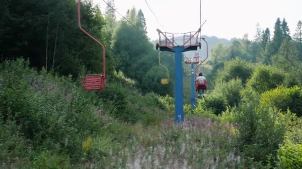 El telesilla más antigua con cables de acero en las montañas de Cárpatos entre el bosque de pinos verdes con flores y hierba. Telesilla pasando por el paso de montaña — Vídeos de Stock