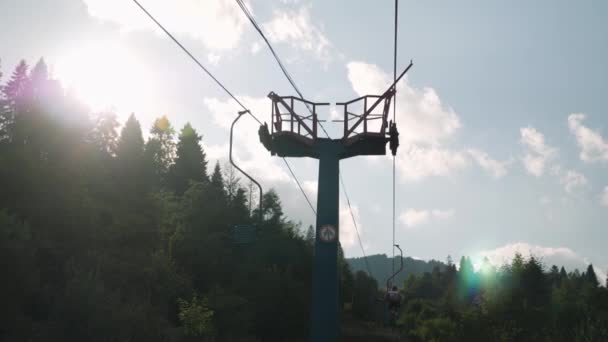 Stolslyft med stålkablar mot blå himmel och gröna träd. Stolslyft i Karpaterna på sommaren — Stockvideo