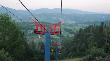 Kayak teleferiği geçerken yaklaşın. Dağlarda çelik kayak telleri. Sandalye kaldırma mekanizması. Yeşil ormanda çelik halat çekme.