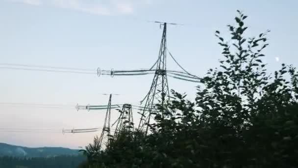 Transmission towers in mountains. Power towers against sunset sky. Electric towers in green forest at dusk — Stock Video