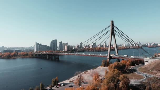 Stor betongbro med stålrep som förbinder två stora storstadsbankar. Flygdrönare vy över bron med upptagen biltrafik, Kiev, Ukraina — Stockvideo
