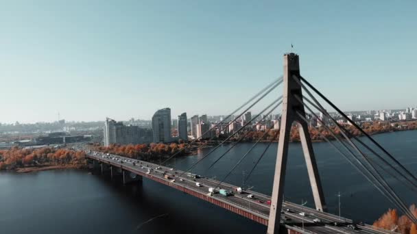 Yüksek binaları ve köprüsü olan endüstriyel şehir merkezinin inanılmaz hava manzarası. Arabalarla dolu beton köprü. Metropolis 'te nehrin yanında uçan insansız hava aracı. Kyiv, Ukrayna — Stok video