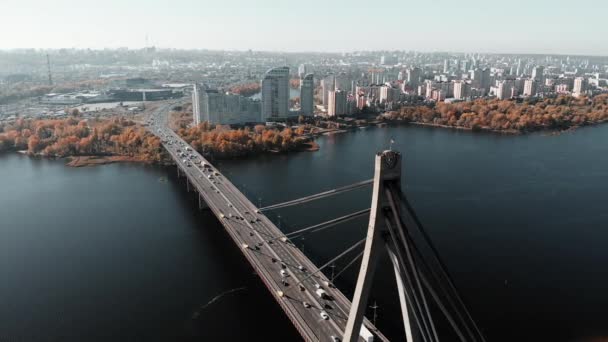 Incrível vista drone de Kiev com edifícios altos e construções em segundo plano. Drone voando acima da ponte do carro através do rio largo na metrópole grande — Vídeo de Stock