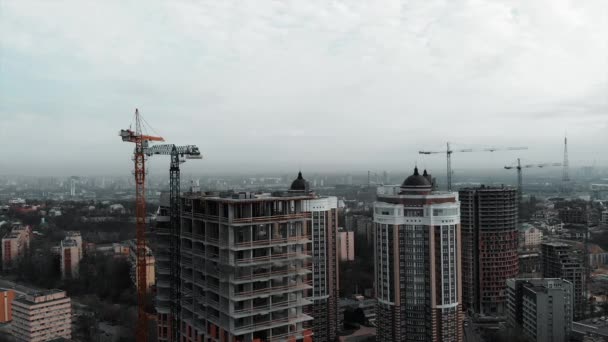 Будівництво житлового будинку. Вид з повітряного безпілотника в центрі міста з висотними будівлями в сірий хмарний день. Нові будівельні конструкції мегаполісу — стокове відео
