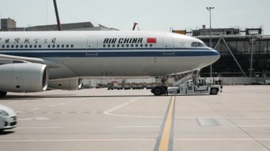 Cenevre / İsviçre - 22 Temmuz 2019 - Air China havayolları uçağı, Airbus A330-200 Cenevre havaalanında uçuş için hazırlanıyor. Havaalanı çalışanı kalkış için uçak hazırlıyor.