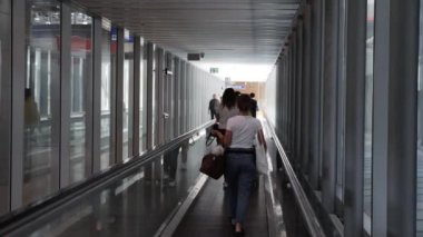 Cenevre / İsviçre - 22 Temmuz 2019 - kadın ve erkek yolcuların el bagajları Cenevre Havaalanı 'nda yürüyen merdiven üzerinde yürümeleri, arka görüş