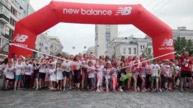 Kyiv / Ukrayna - 2 Haziran 2019 - Mutlu gülümseyen küçük kızlar ve oğlanlar başlangıç çizgisini ve şişirilebilir kemeri geçerek Color Run 'daki boya festivalinde şehir merkezinde koşmaya başladılar