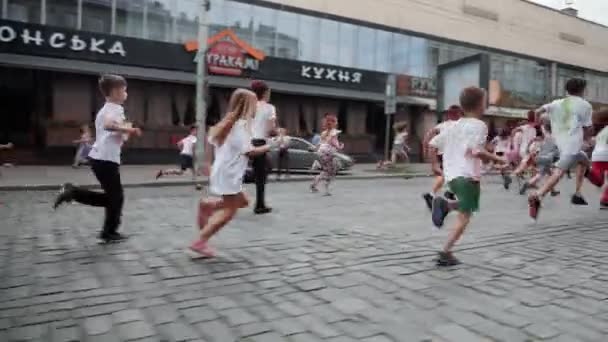 Kyiv/Ukraine - June 2, 2019 - Happy charming little children in white t-shirts intensive running in city center at paint festival at Color Run — Stock Video