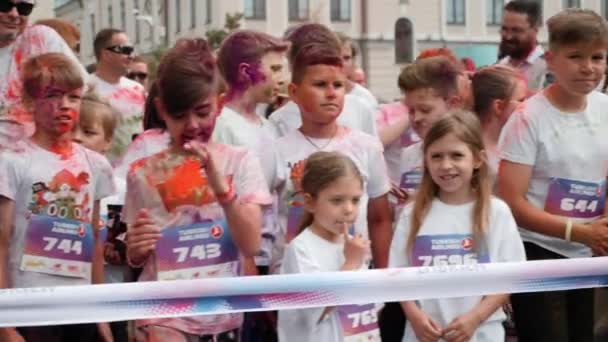 Kiev / Oekraïne - 2 juni 2019 - Gelukkige zelfverzekerde kleine jongens en meisjes in fluorescerende kleurrijke verven die aan de startlijn staan voor de start van de race Color Run — Stockvideo