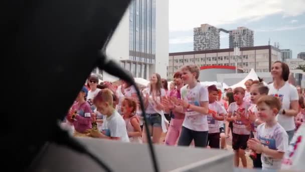 Kiev / Oekraïne - 2 juni 2019 - Gelukkige glimlachende meisjes en jongens dansen bij het podium op Color Run Kiev — Stockvideo