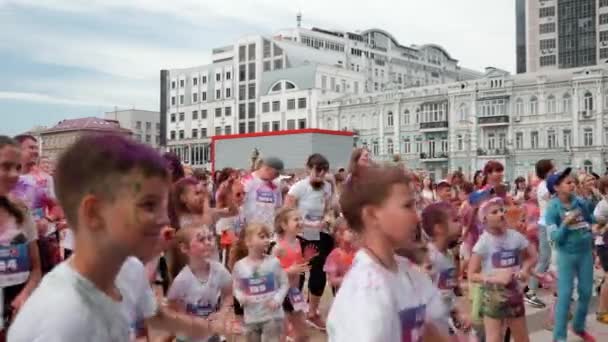 Киев / Украина - 2 июня 2019 года - Группа счастливых детей, запятнанных красочными холи-красками, танцующих у сцены на Color Run Kyiv — стоковое видео