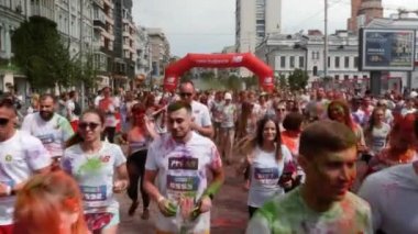 Kyiv / Ukrayna - 2 Haziran 2019 - Irk renginin çekici kadın ve erkek katılımcıları şehir merkezine renkli floresan Hint holi boyaları sürmüş beyaz tişörtlerle koşuyor