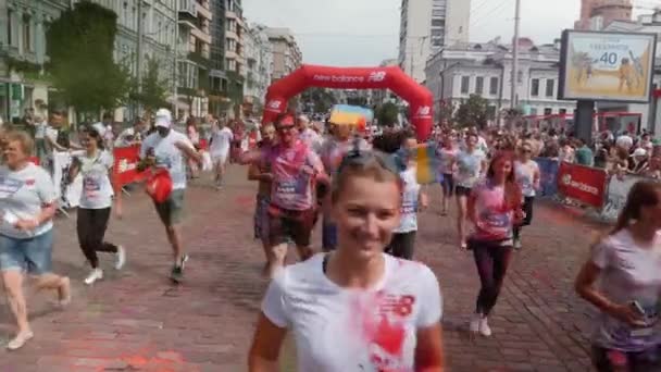 Kiev / Oekraïne - 2 juni 2019 - Grappige mensen in witte kleren zijn gekleurd kleurrijke holi verven joggen langs het centrum van de stad op verven festival op Color Run — Stockvideo