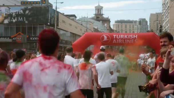 Kijów / Ukraina - 2 czerwca 2019 - Widok z tyłu uroczych kobiet i mężczyzn biegaczy w białych ubraniach biegają pod nadmuchiwanym łukiem na festiwalu farb w Color Run — Wideo stockowe