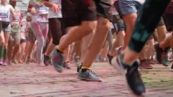 Kiev / Ukraine - 2 juin 2019 - Vue rapprochée des jambes en baskets des participants de Color Run teintées de peintures holi indiennes fluorescentes colorées courant le long du centre-ville au festival de peintures — Video