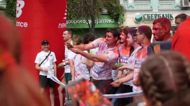 Kiev / Ukraine - Le 2 juin 2019 - Les femmes et les hommes caucasiens souriants heureux en t-shirts blancs sont enduits de peintures holi colorées debout à la ligne de départ avant le début de la course Color Run — Video