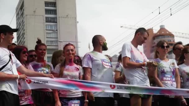 Kyiv/Ukraine - June 2, 2019 - Portrait of young people stained in colorful holi paints standing near starting line and inflatable arch at Color Run — Stock Video