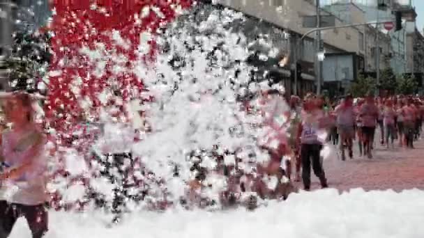 Kiev / Ukraine - Le 2 juin 2019 - Des jeunes gens heureux teints de peintures fluorescentes colorées holi jogging à travers la mousse à Color Run — Video