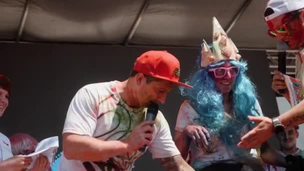 Kyiv/Ukraine - June 2, 2019 - oncert's hosts and participants of Color Run in funny fancy costumes stained in colorful fluorescent indian holi paints standing on stage — Stock Video