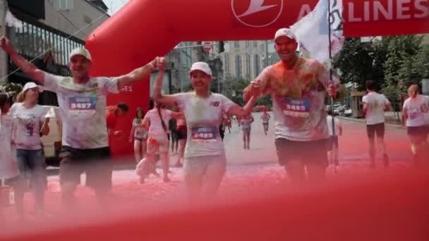 Kiev / Oekraïne - 2 juni 2019 - Groep van gelukkig bedrijf werknemer gekleurd in kleurrijke fluorescerende holi verven over de finish bij Color Run en plezier hebben — Stockvideo