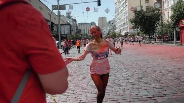 Kyiv/Ukraine - June 2, 2019 - Attractive young caucasian woman stained in colorful fluorescent holi paints running at Color Run and giving five — Stock Video