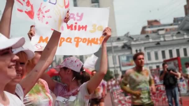 Kiev / Ucrânia - 2 de junho de 2019 - Encantadora jovem rindo de pé com cartaz "Casarei com uma corredora de maratona" no festival de tintas no Color Run — Vídeo de Stock