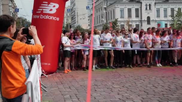 Κίεβο / Ουκρανία - 2 Ιουνίου 2019 - Ευτυχισμένοι άνθρωποι με λευκά ρούχα βαμμένα σε χρώματα φθορισμού holi περιμένουν κοντά στην γραμμή εκκίνησης και είναι έτοιμοι για αγώνα Χρώμα Run — Αρχείο Βίντεο