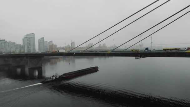 Betong större bro med stålkablar i industriell smog i centrum. Stor pråm lastad med sand flyter på bred bäck under bron i tillverkade centrum, antenn drönare skott — Stockvideo