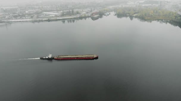 Major old iron barge loaded with sand is sailing on the river along industrial downtown in smog. Scow is floating in fog at industrialized city, aerial top view — Stock Video