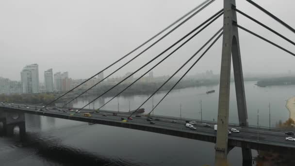 Ponte cinza de concreto enorme com cabos de aço é combinado dois lados da metrópole em névoa industrial. Carros e transportes públicos com tráfego pesado estão andando através do rio na ponte, vista aérea superior — Vídeo de Stock