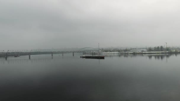 Big lonely old iron barge is floating on river. Scow is sailing through fog on river of industrial city, aerial drone view — Stock Video